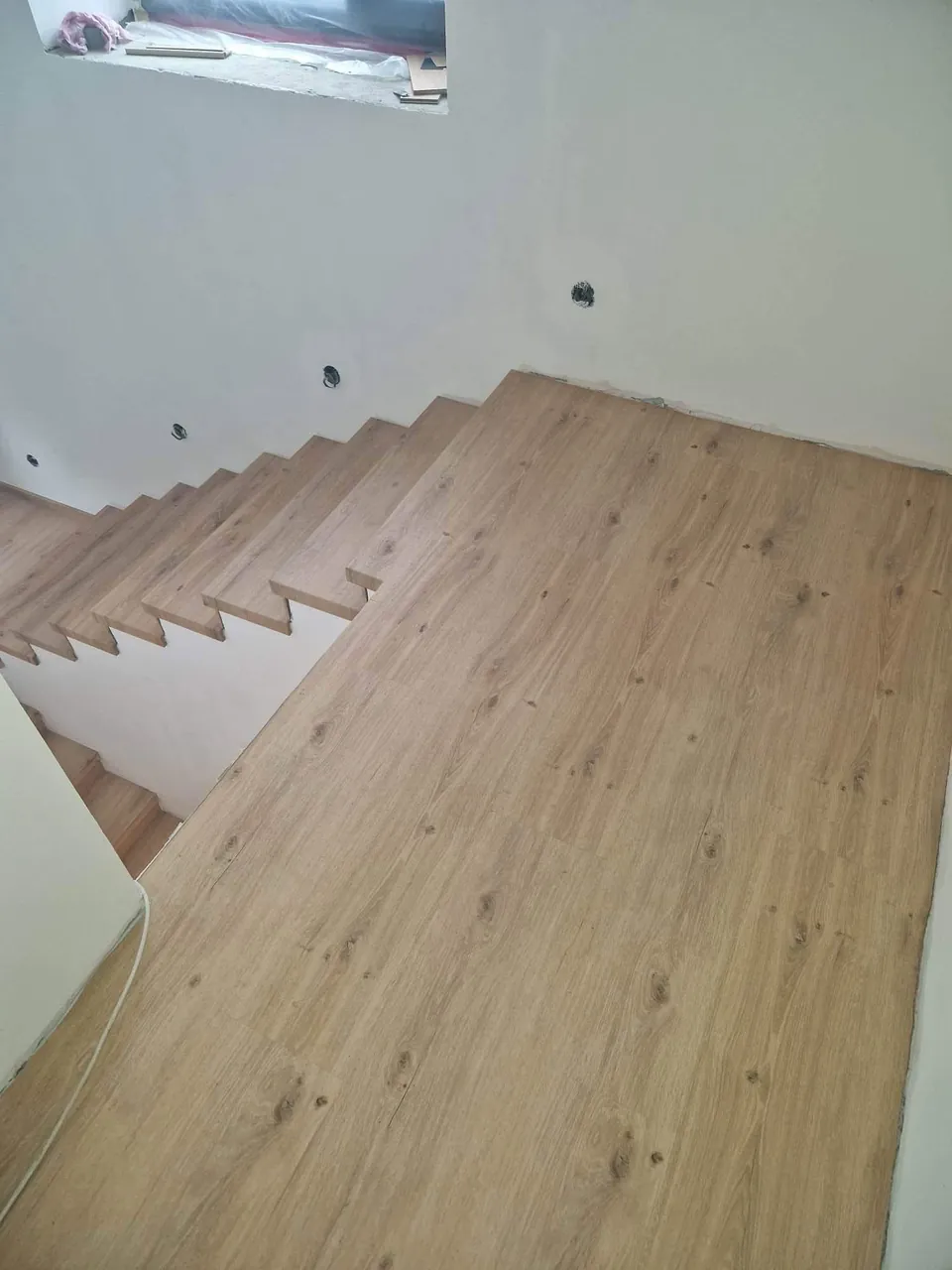 Nová podlaha v dekoru dubu navazující na obložené schody