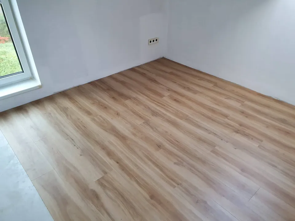 Prázdný pokoj s novou podlahou v dekoru dubu