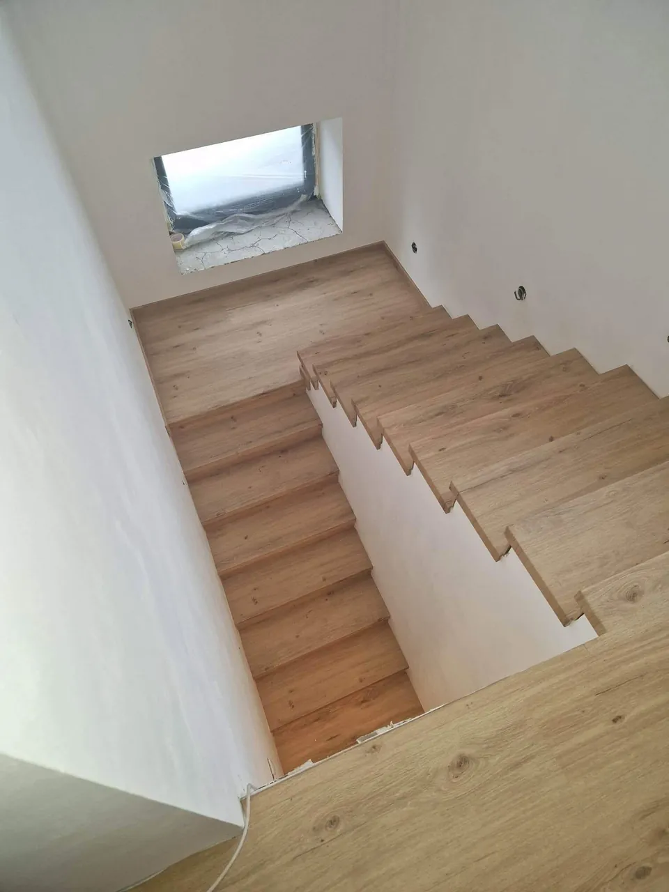 Pohled shora na obložené schodiště s podestou
