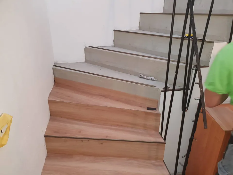 Schodiště s černým zábradlím během obkládání podstupnic